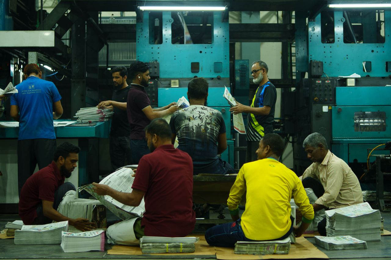 services-05 A team of workers sorting newspapers in an industrial printing factory.